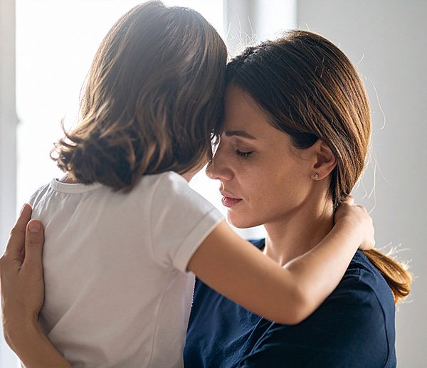 Caregiver and child share quiet embrace, symbolizing concerns about bonding or attachment explored through therapeutic assessment.