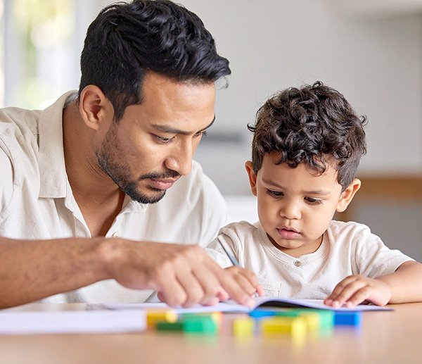Parent and child engaged in early learning activity, reflecting developmental concerns such as speech or social-emotional delays.