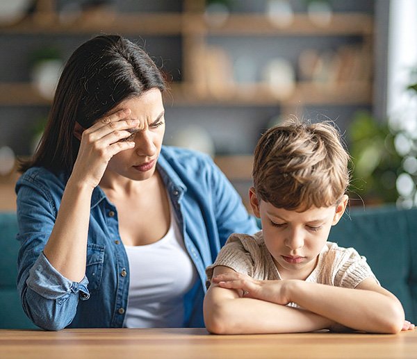 Concerned parent and withdrawn child at table, representing behavioral shifts after stressful life events or transitions.