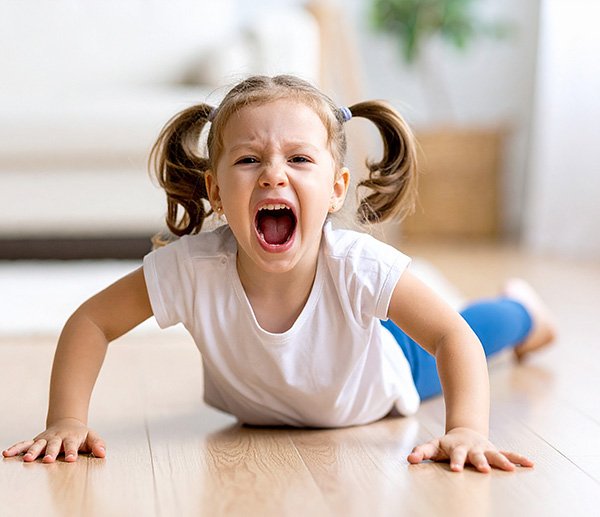 Young child screaming during a tantrum on the floor, illustrating emotional outbursts addressed through psychological assessment.