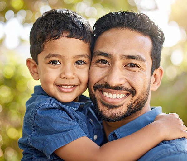 Smiling father and child hugging outdoors, symbolizing connection and insight into parenting a sensitive or spirited child.