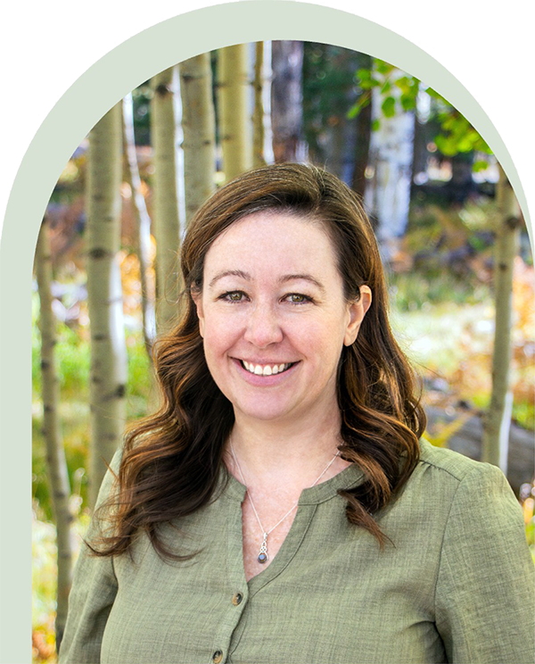 Portrait of Dr. Nicole Wolf smiling outdoors with aspen trees behind her, symbolizing grounded, compassionate psychological care.